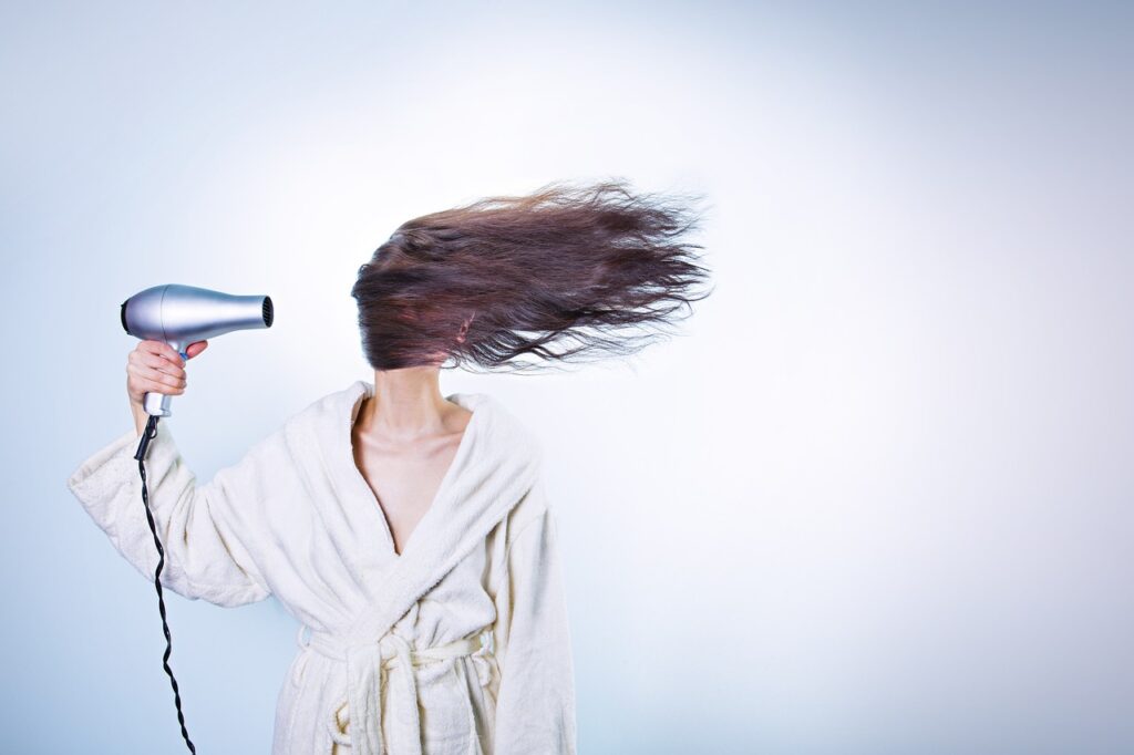 ヘアドライヤーで髪を乾かしている女性